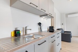 A modern kitchen with a stainless steel sink, white cabinets, and a grey chair. - Apartment 'Pink Lady' with Mountain View & Large Balcony (Lana)