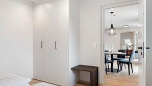A bedroom with a bed, a wardrobe, a small desk, and a dining area with chairs and a table. - Apartment 'Pink Lady' with Mountain View & Large Balcony (Lana)