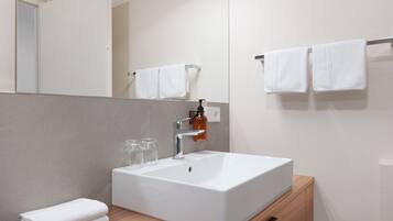 A modern bathroom with a white sink, a mirror, and two towels on a towel rack.