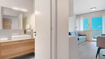 A modern bathroom with a large mirror, wooden vanity, and a white sink.