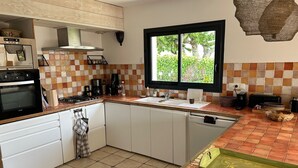 A kitchen with a tiled backsplash, a window with a view, and a stove. - KERALORH - Holiday home for rent in La Trinité sur Mer  - S1 (La Trinité-sur-Mer)