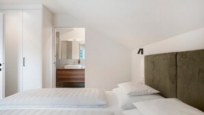 Ein Schlafzimmer mit Bett, Kleiderschrank und angrenzendem Badezimmer.