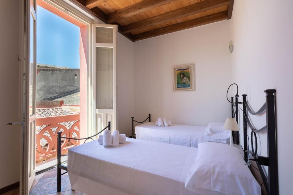 A hotel room with two beds, a balcony, and a painting on the wall.