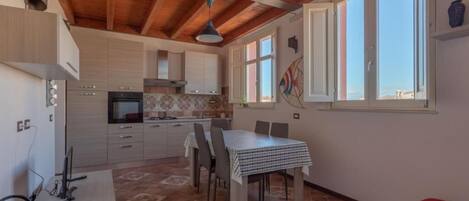 A kitchen with wooden beams, a dining table, and a red sofa.
