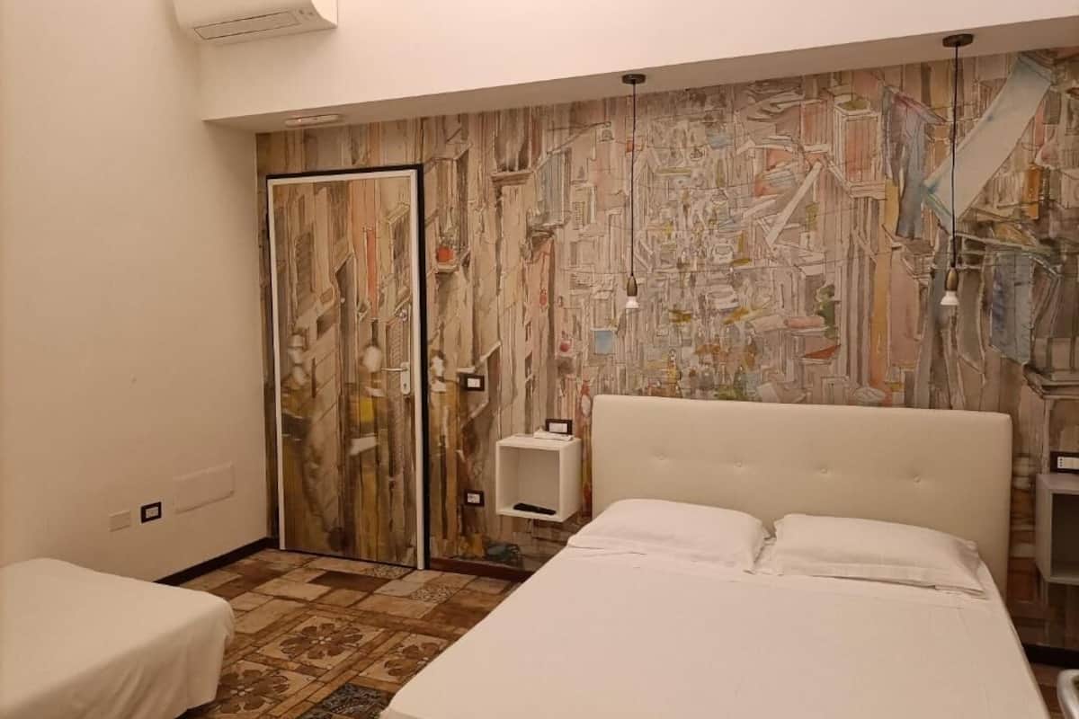 A hotel room with a bed, a bedside table, a wardrobe, and a patterned wall.