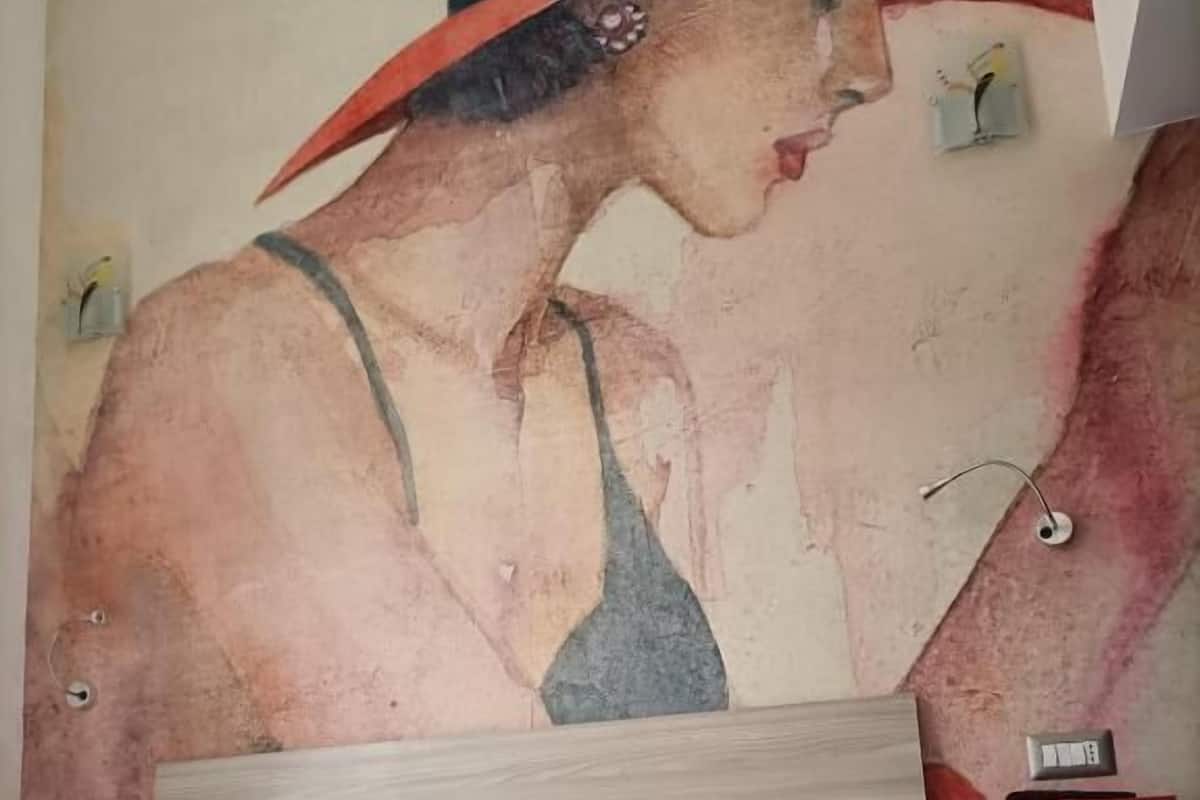 A hotel room with a bed, a nightstand, and a wall with a painting.