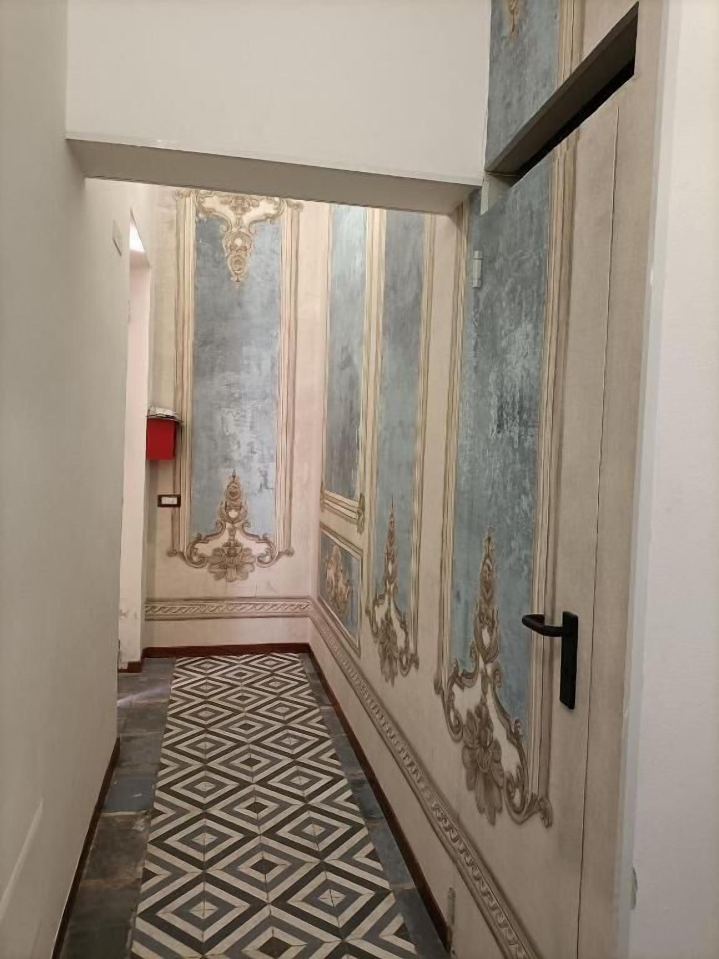 Un couloir doté d’un sol à motifs et de décorations murales élaborées.