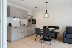 Una cocina moderna con gabinetes grises, una mesa de comedor con sillas y una lámpara colgante.