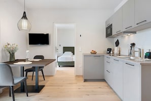 A modern kitchen with a dining area, a TV, and a bed in the background. - Apartment 'Red Delicious' with Mountain View & Large Balcony (Lana)