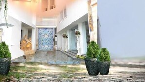 A hotel entrance with a modern design, featuring a prominent 'SBK' sign, a glass facade, and a decorative entrance with steps and potted plants. - SBK Park Inn (Kanchipuram)