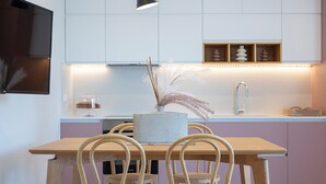 A modern kitchen with a dining table and chairs, a built-in oven, and a sink. - Lirides Suites (Lefkada)