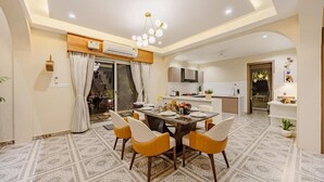 A modern dining area with a table set for four, surrounded by yellow chairs, and a kitchen in the background. - Heaven in Hills By ELIVAAS with pvt pool (Māvli)