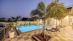 A swimming pool with a checkered floor, surrounded by potted plants and lounge chairs. - Heaven in Hills By ELIVAAS with pvt pool (Māvli)