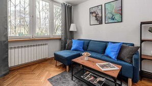 Moderni olohuone, jossa on sininen sohva, puinen sohvapöytä ja patteri.