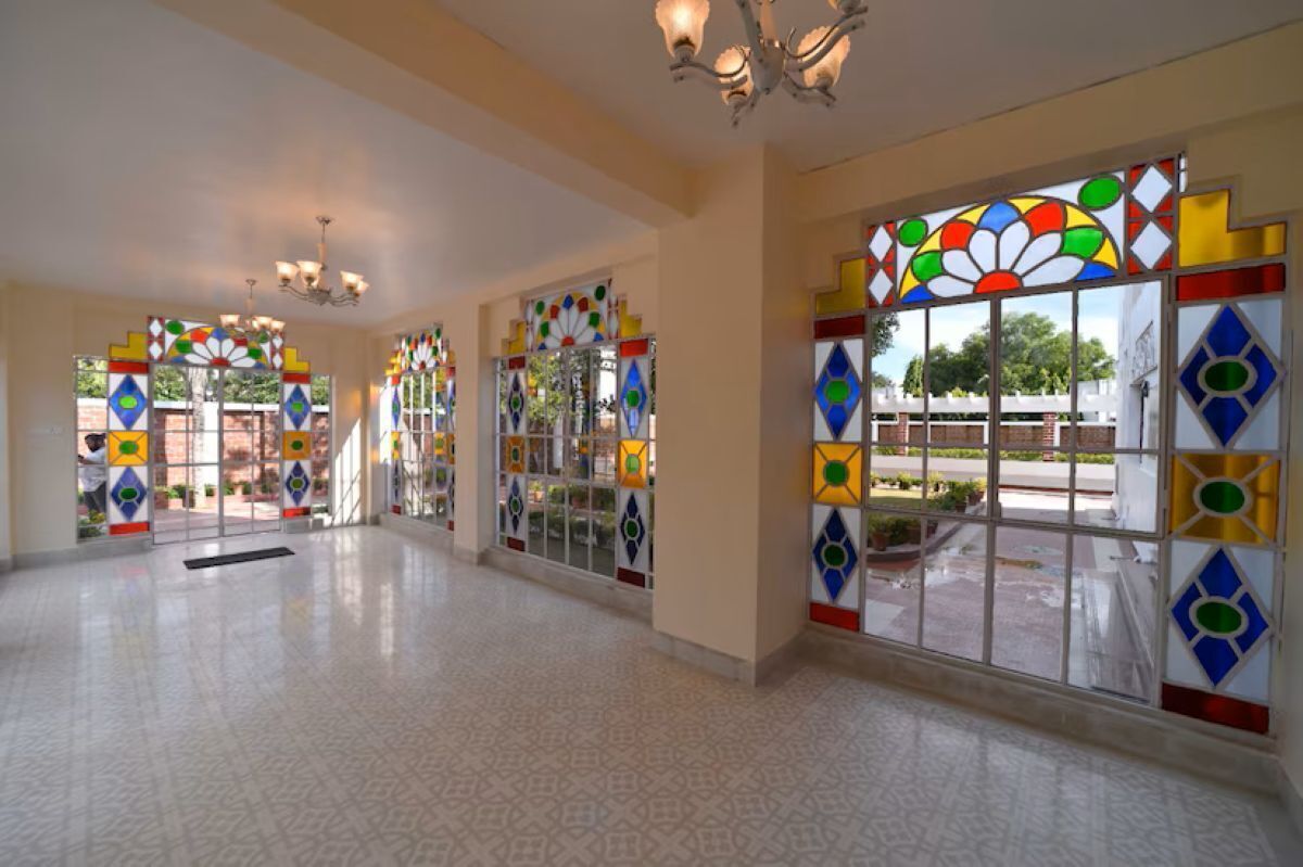A spacious hallway with patterned flooring and large windows with colorful stained glass.