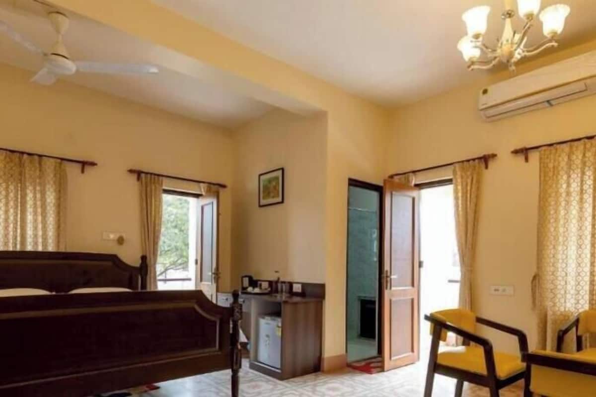 A hotel room with a bed, a desk, a chair, and a ceiling fan.