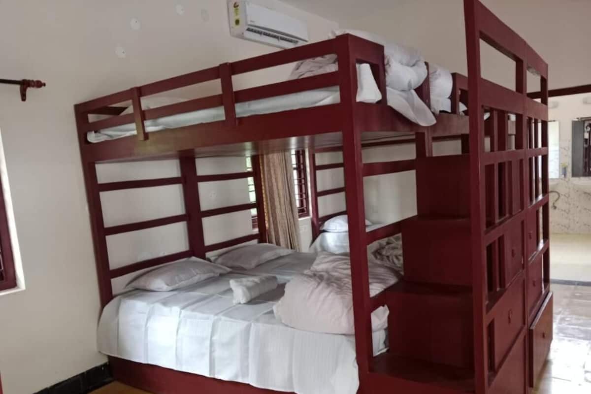 A bunk bed with a wooden frame, white bedding, and a window with curtains.
