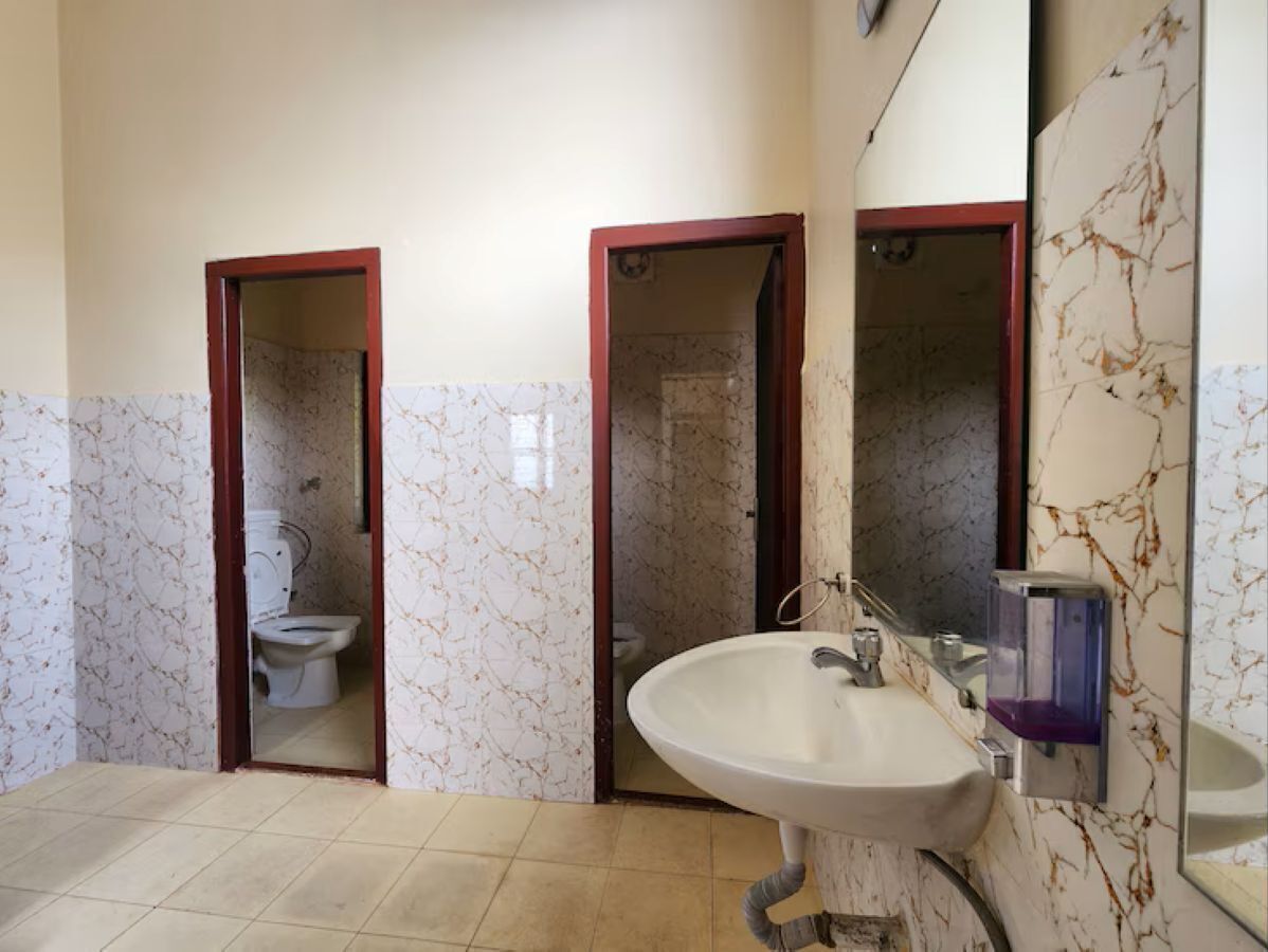 A bathroom with a toilet, sink, and mirror.