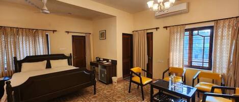 A hotel room with a bed, a desk, a chair, a table, and a window.