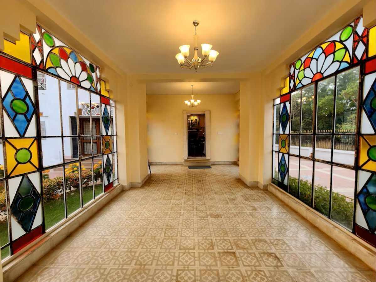 A hallway with patterned floor tiles, a chandelier, and stained glass windows.