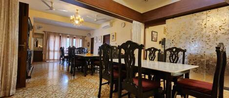 A dining area with a patterned floor, wooden chairs, a central table, and a staircase leading to an upper level.