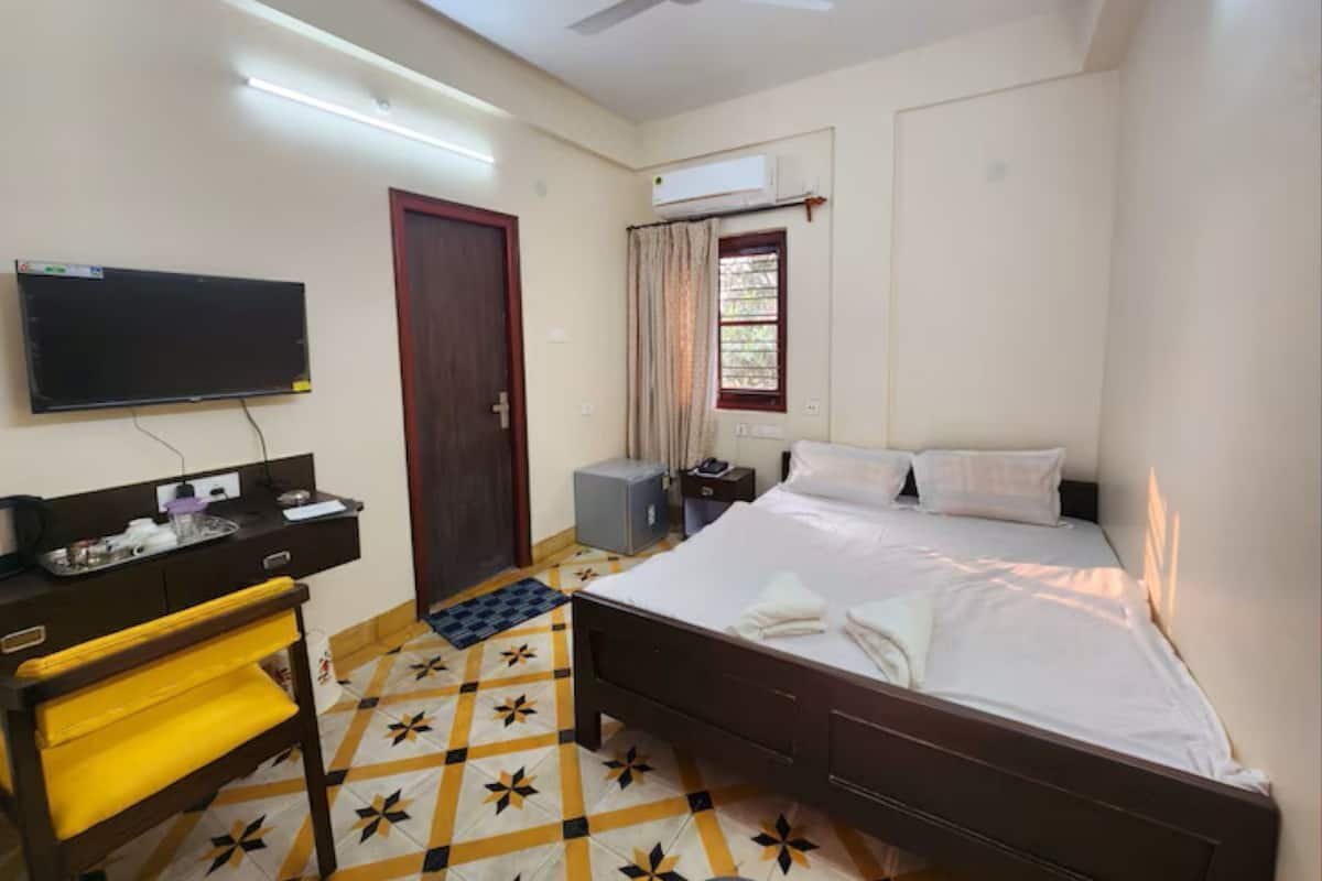 A hotel room with a bed, a desk, a chair, a television, and a ceiling fan.