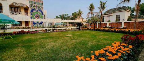 A courtyard with a lawn, a flower bed with orange flowers, and a building with a colorful mural.