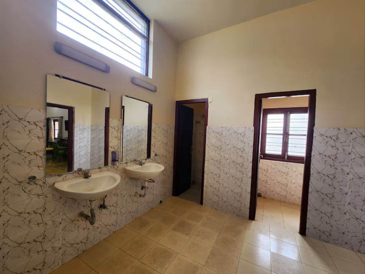 A bathroom with two sinks, a mirror, and a door leading to another room.