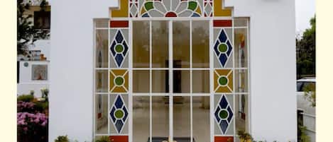 A building with a white facade, a decorative entrance with a glass door, and a sign with text.
