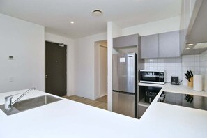 Eine moderne Küche mit weißen Arbeitsplatten, Edelstahlgeräten und einem eingebauten Backofen.
