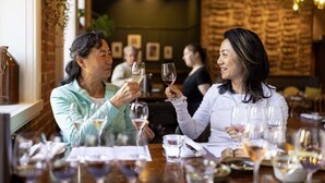 Interior de restaurante con paredes de ladrillo, cuadros enmarcados y mesas dispuestas para comer.