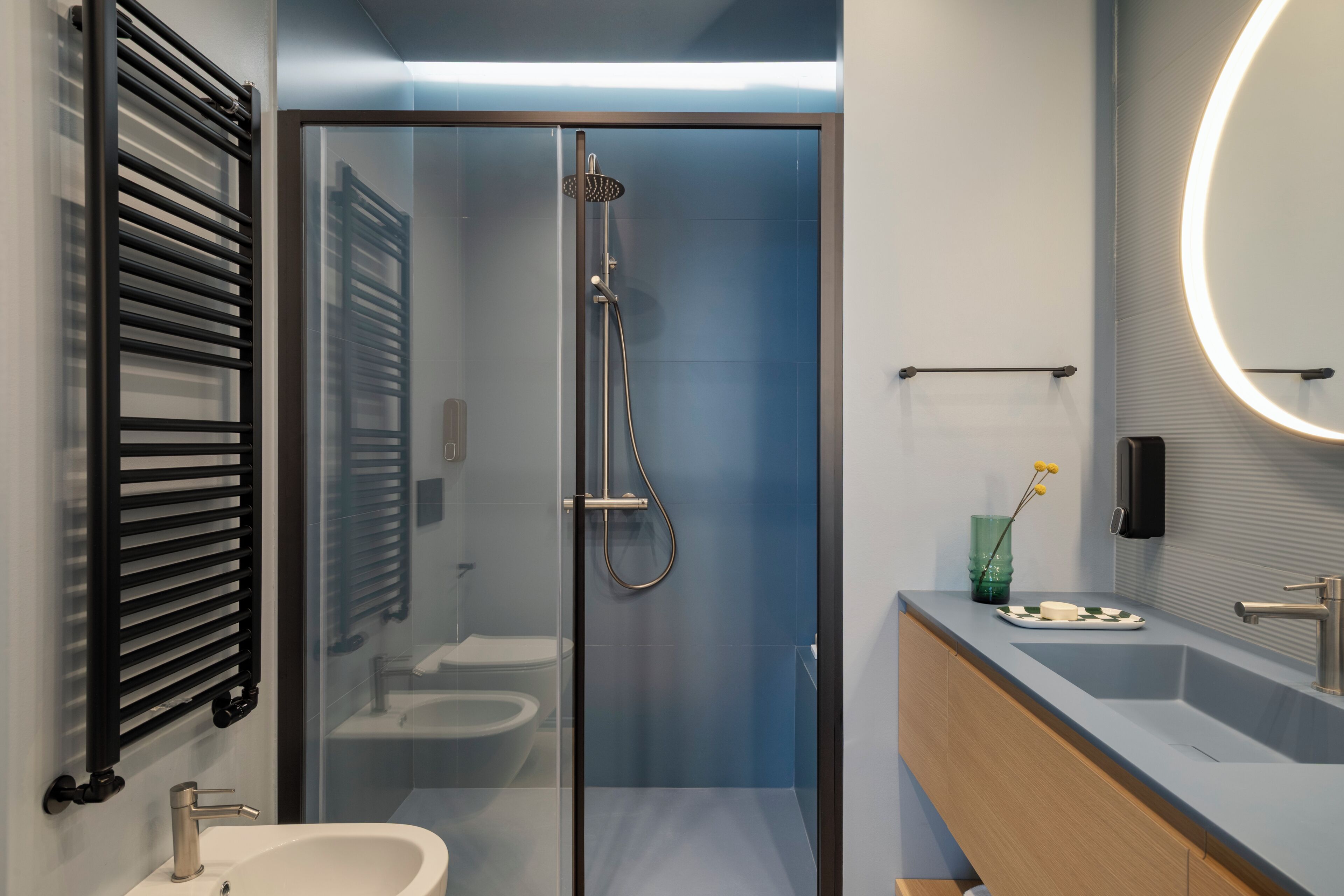 Un baño moderno con ducha de vidrio, lavabo, espejo y toallero.
