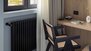 A room with a window, a radiator, a desk with a chair, and a wall with a tree pattern.