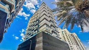A high-rise building with a zigzag architectural design, featuring multiple balconies and a glass facade. - Premium 1BR with Great Amenities in JVC (Dubai)