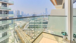 A high-rise building with a glass balcony overlooking a cityscape. - Premium 1BR with Great Amenities in JVC (Dubai)