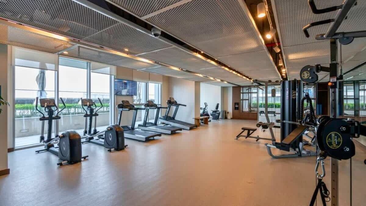 A gym with treadmills, weight machines, and a large window offering a view of the outdoors.