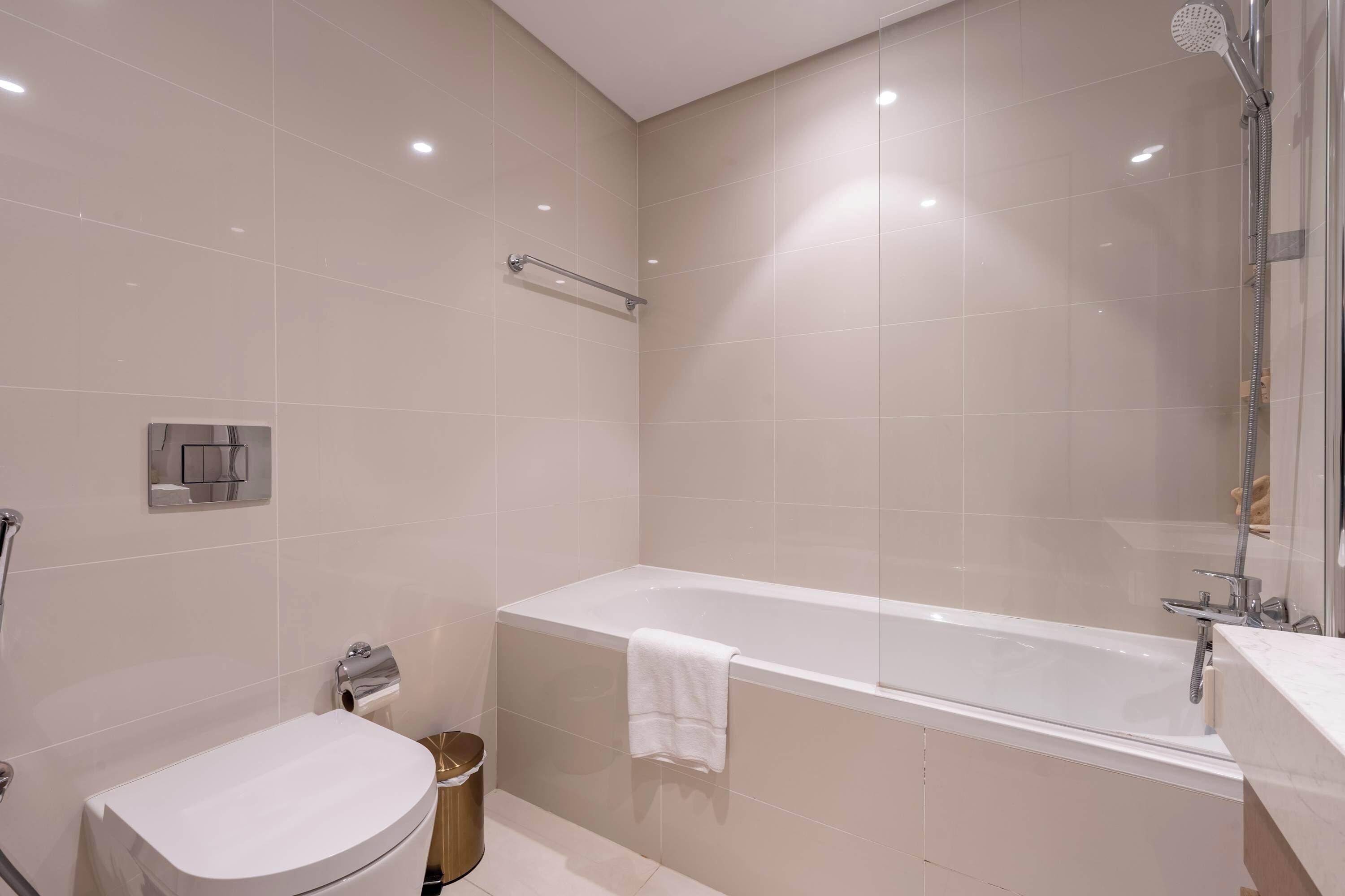 A modern bathroom with a bathtub, toilet, and shower.