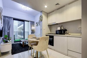 A modern kitchen with a dining area, featuring a built-in oven, a coffee maker, and a sink. - Chic and Cozy 1BR Retreat - Canal and City View (Dubai)