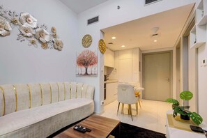 A modern living room with a sofa, a coffee table, and a dining area with a chair and table. - Chic and Cozy 1BR Retreat - Canal and City View (Dubai)