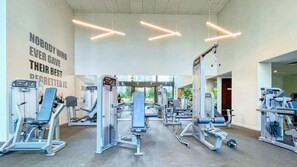 A modern gym with various exercise machines, motivational wall text, and a spacious layout. - Luxury 2BR Family Living - Premium Amenities (Dubai)