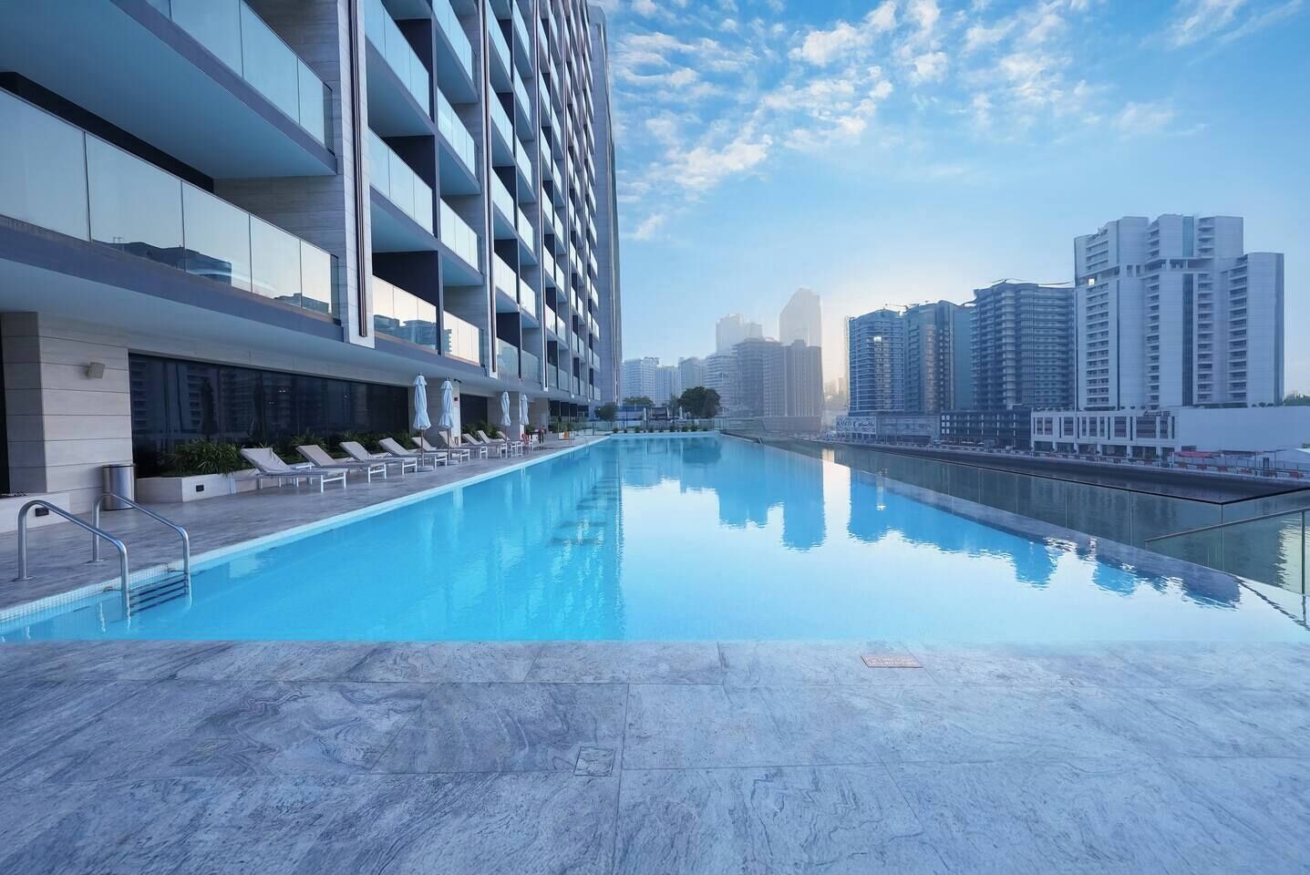 A modern hotel with a rooftop infinity pool, offering views of the city skyline.