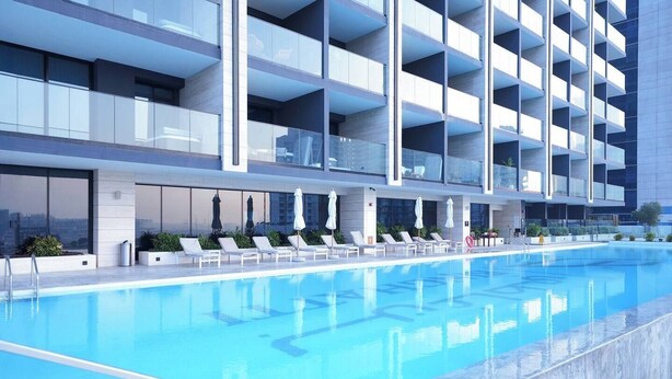 Ett modernt hotell med en stor pool, flera balkonger och solstolar.