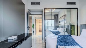 Una habitació d'hotel moderna amb un llit, una taula de nit i un mirall gran.