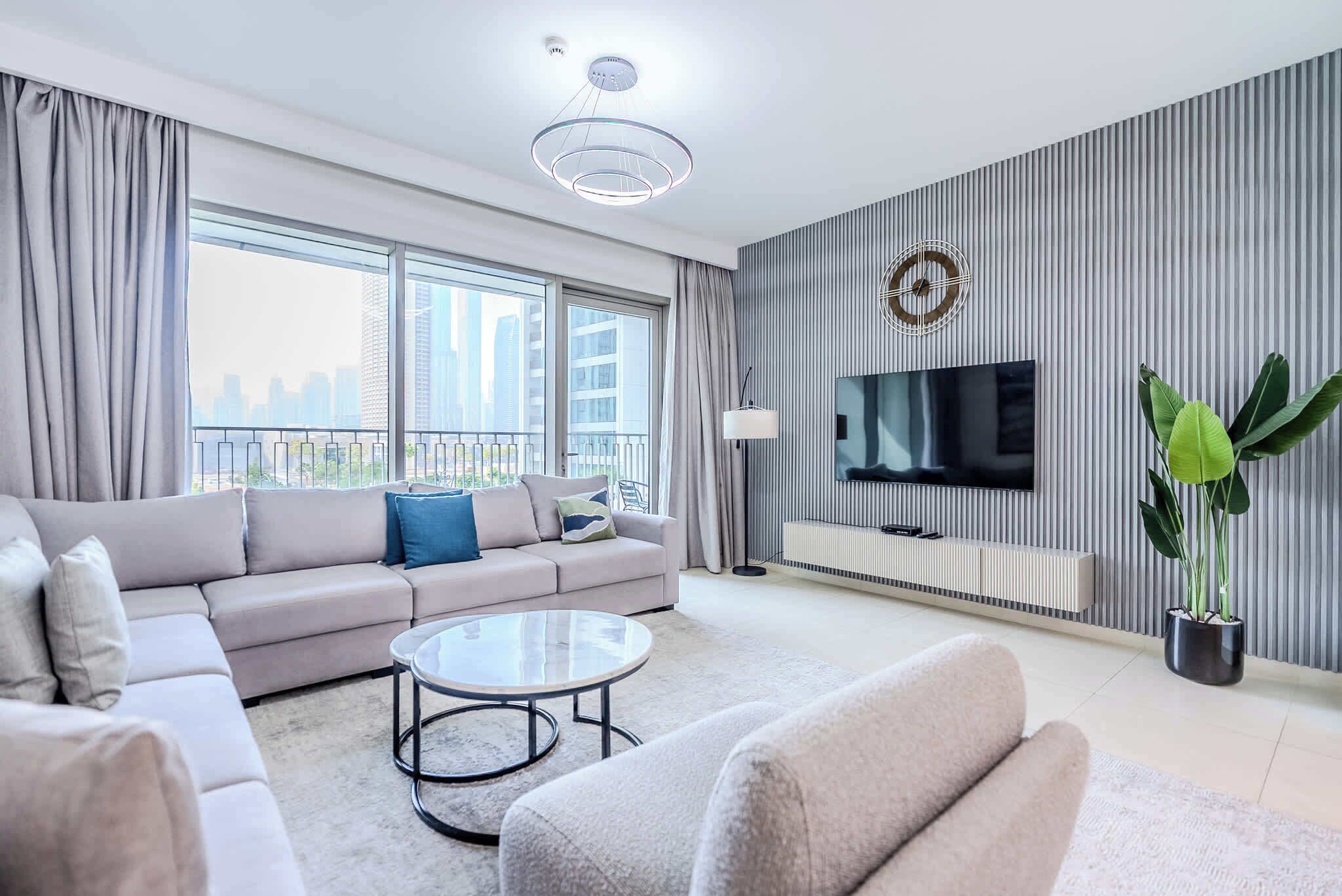 A modern living room with a sofa, coffee table, and a TV against a striped wall.