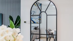 Ein modernes Wohnzimmer mit einem Ecksofa, einem Esstisch mit Stühlen und einem großen abstrakten Gemälde an der Wand.