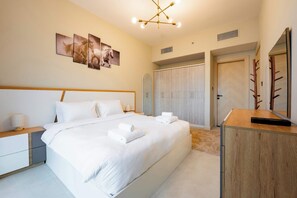 A modern hotel room with a large bed, a wooden nightstand, a desk, and a wardrobe. - Pool View, Fully Furnished, Prime JVC Location (Dubai)