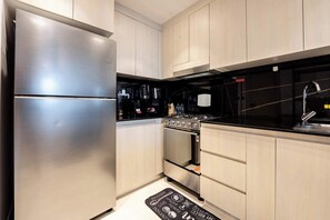 A modern kitchen with stainless steel appliances, light wood cabinets, and a black countertop. - Pool View, Fully Furnished, Prime JVC Location (Dubai)