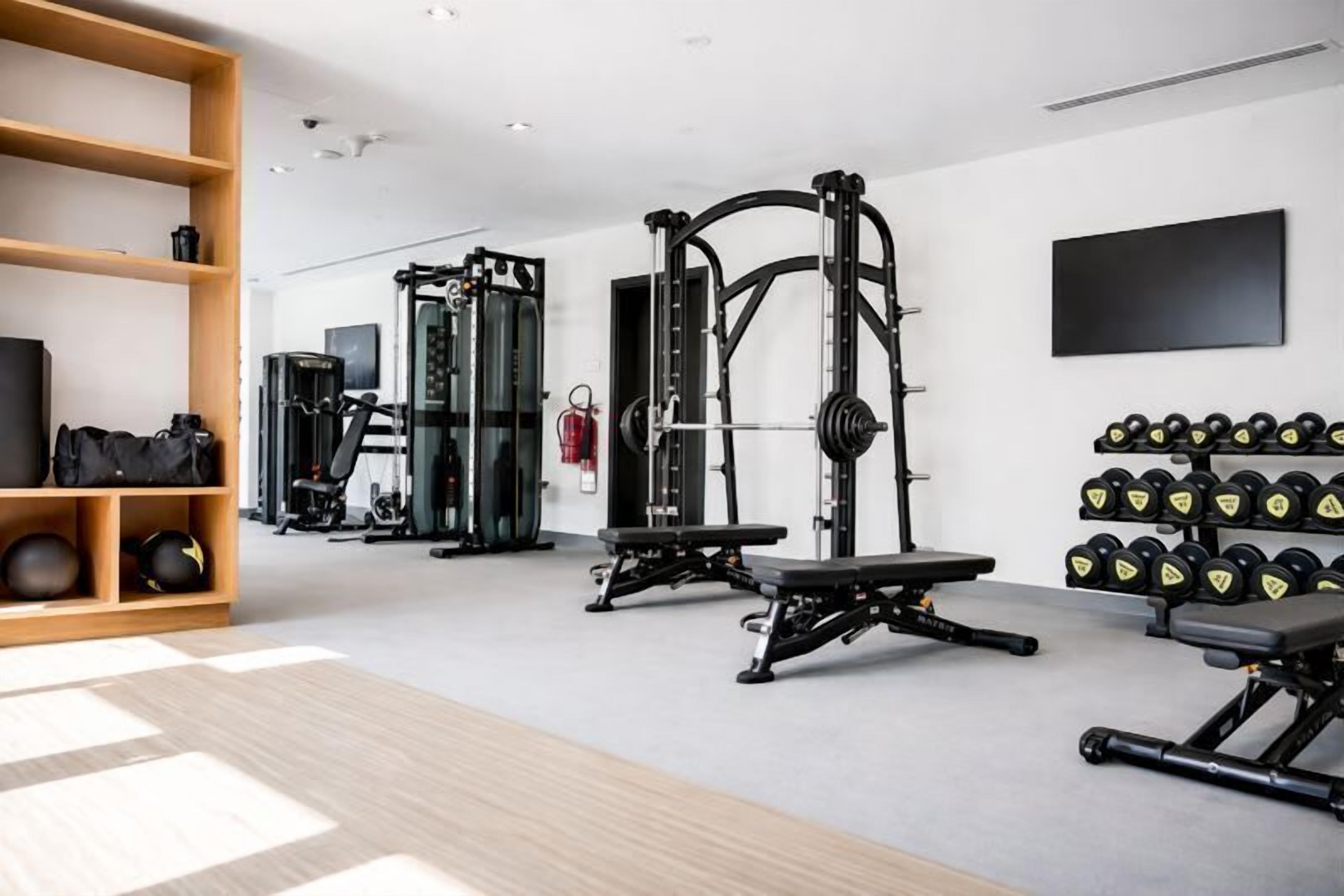 Ett modernt gym med olika typer av träningsutrustning, inklusive en knäböjsställning, en bänkpress och hantlar.