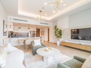 A modern living room with a dining area, kitchen, and a large TV. - Premium 2BR at City Walk, High-End Furnished (Dubai)