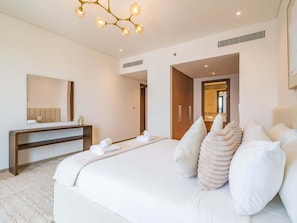 A modern hotel room with a large bed, a bedside table, a mirror, and a unique ceiling light fixture. - Premium 2BR at City Walk, High-End Furnished (Dubai)